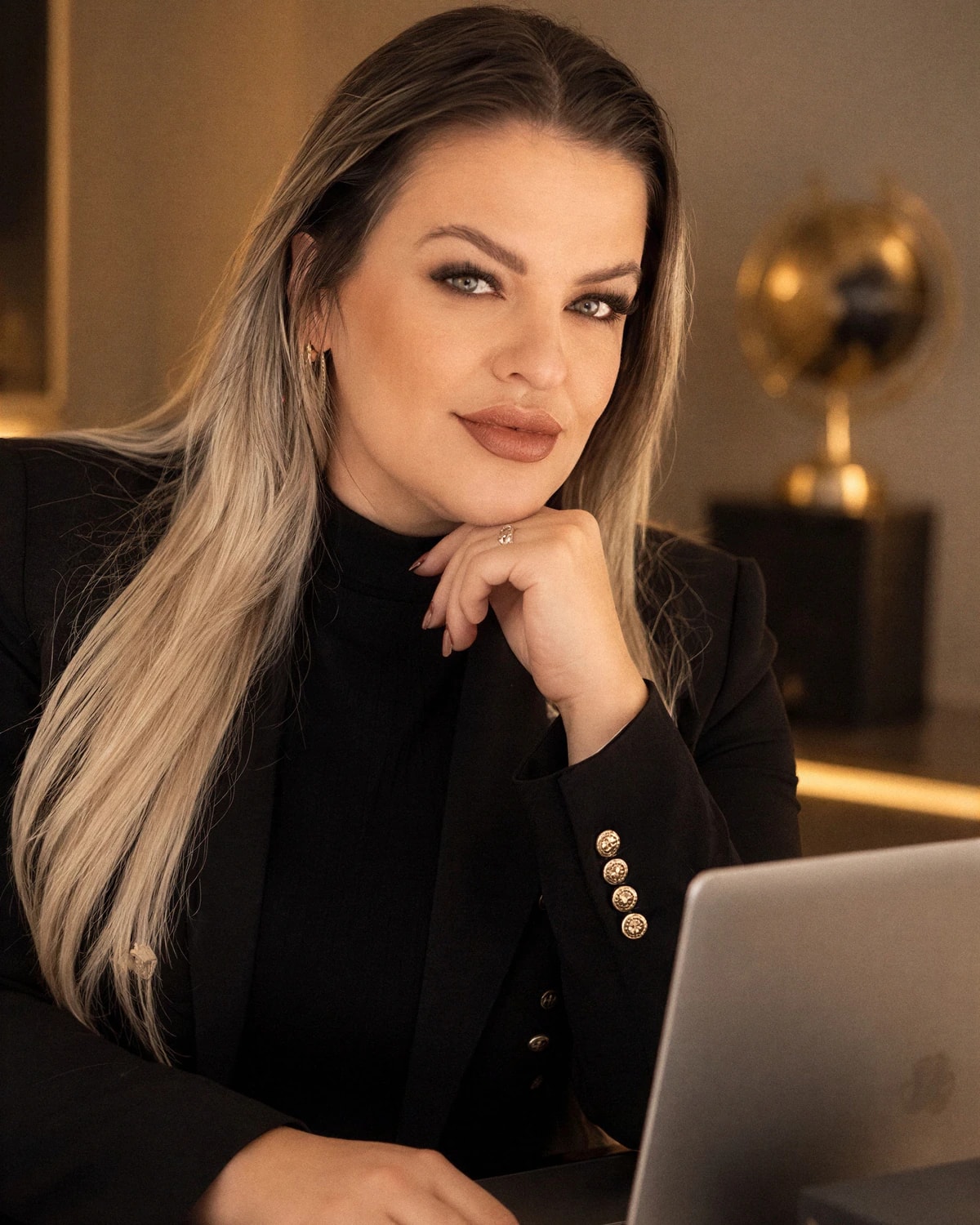 Daniela Silva sentada diante do notebook, em estúdio com luz quente